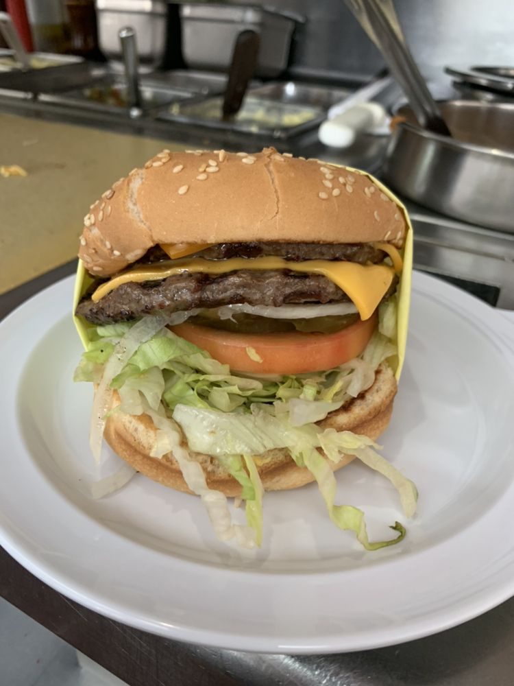 Double cheeseburger with lettuce, tomato and pickles on a plate at Pete's Blue Chip counter