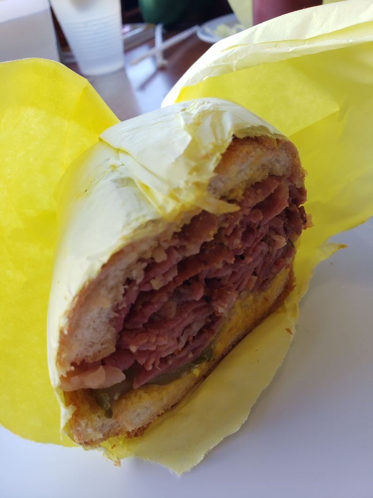 Pastrami sandwich cut in half and stacked high with meat, wrapped in yellow paper